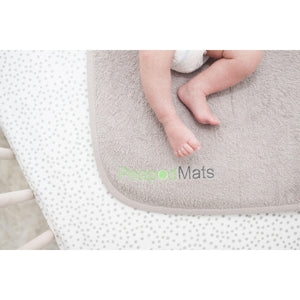 PeapodMats washable, reusable waterproof 1.5'x1.5' chair pad for bed wetting and incontinence, product illustration in sand with baby's legs kicking